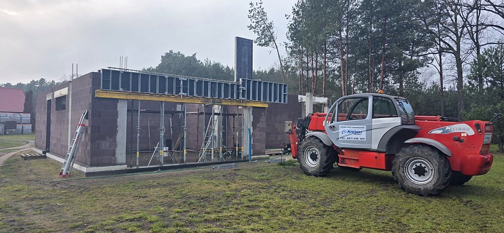 Boruja Nowa, ładowarka teleskopowa z naklejką firmy przy ścianach z keramzytu